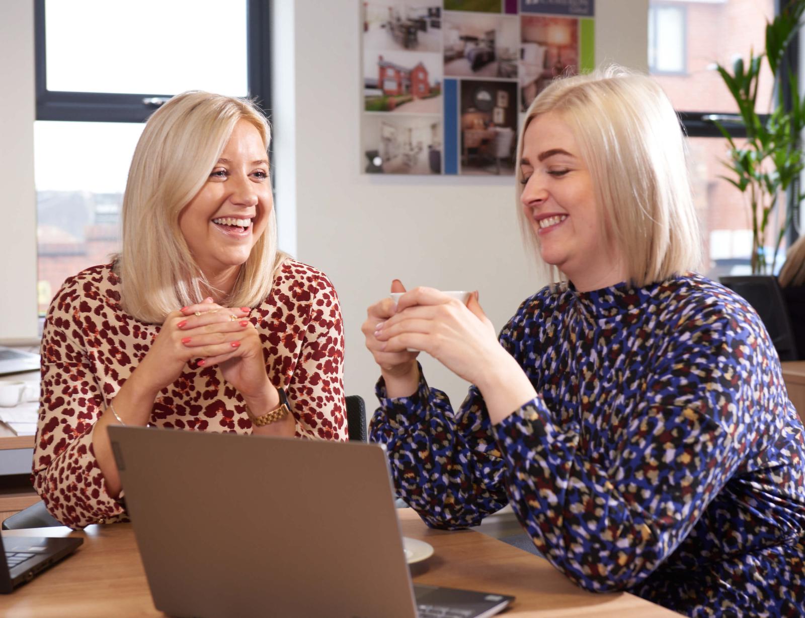 2 co-workers sitting at desk with laptop 